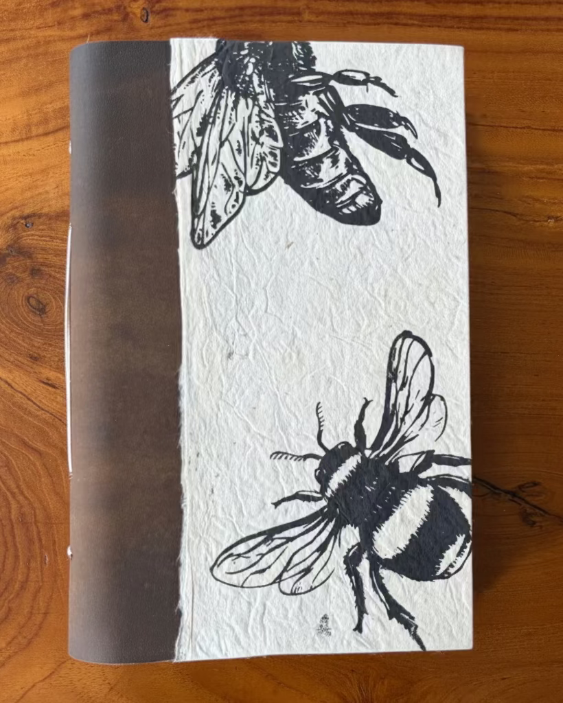 Notebook with bee illustrations on a wooden surface