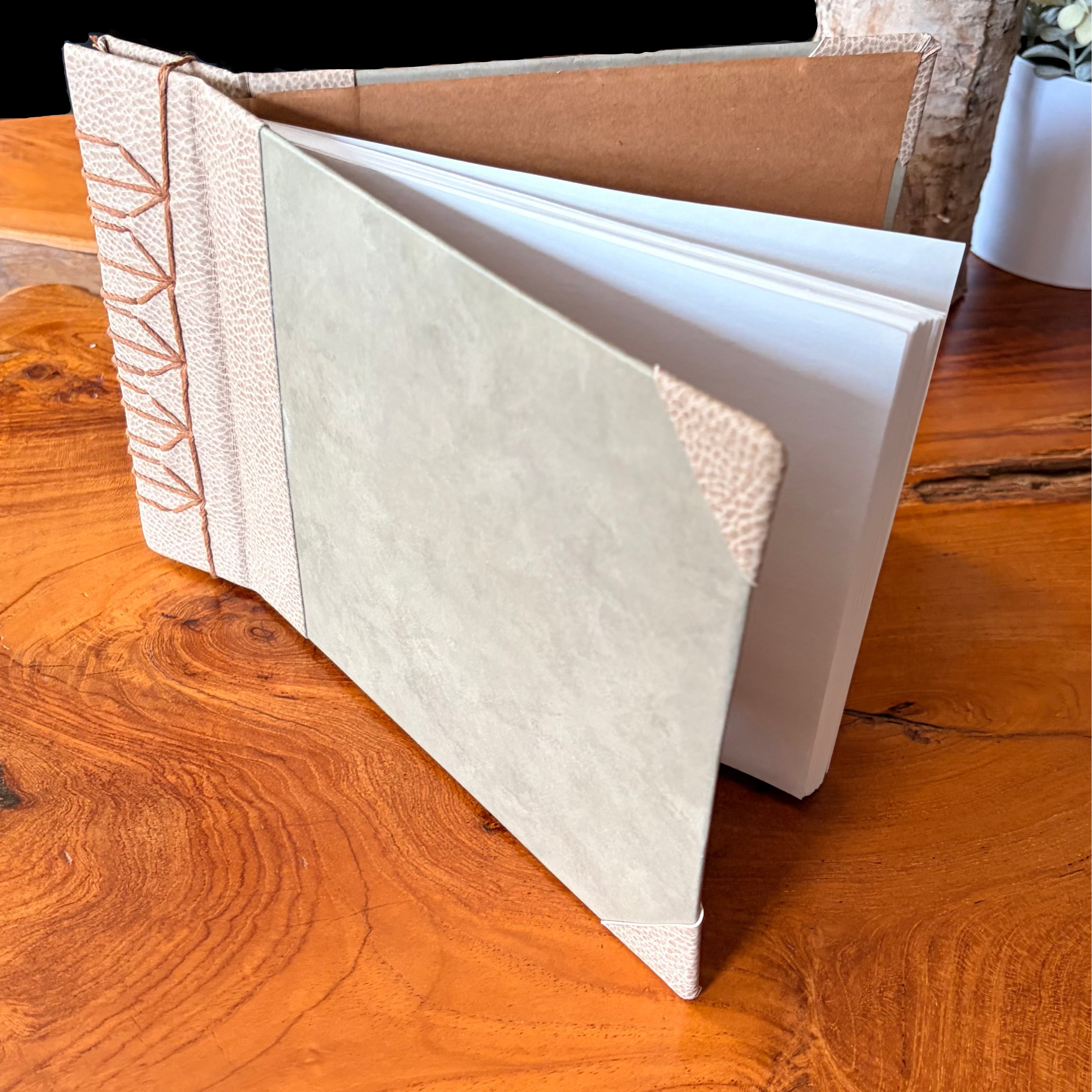 Open leather-bound book on a wooden surface with decorative elements.